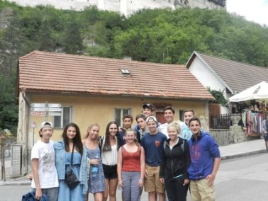 The team in front of a yellow house on a hillside